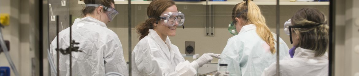 Four students in a lab wearing personal protective equipment
